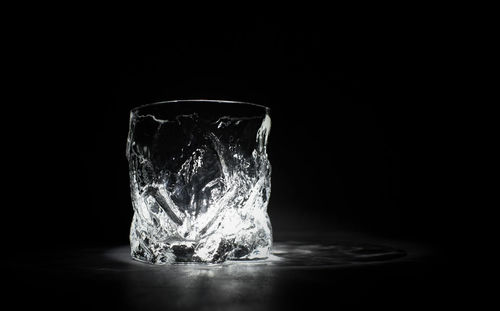 Close-up of ice on table against black background
