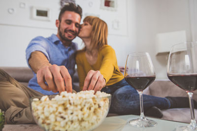 Woman kissing man while sitting on sofa at home