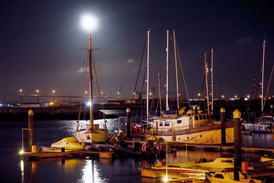 Boats moored in harbor at night