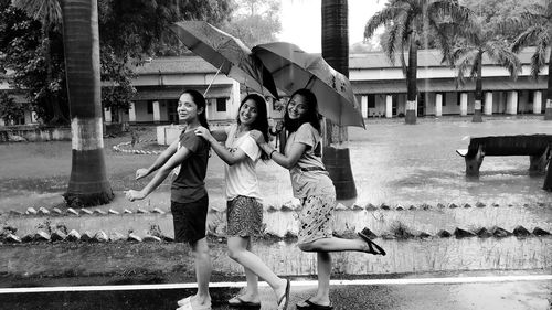 Friends with umbrella in rainy season playing
