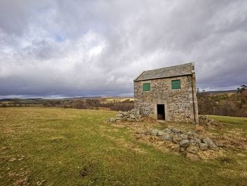 Abandoned house on field against sky