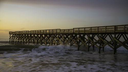 Pier over sea against sky at sunset