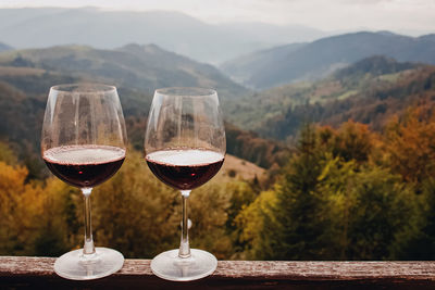 Two glasses of red wine standing with a beautiful scenic mountain view. 