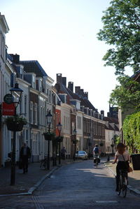 People walking on road in city against clear sky