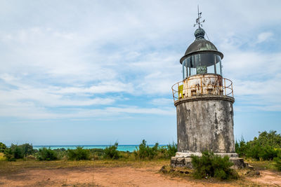 Lighthouse on field against sky