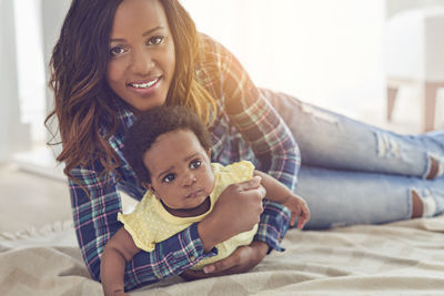 Portrait of mother with cute baby daughter at home