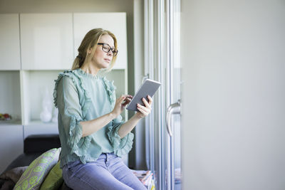 Mature woman sitting on couch using tablet