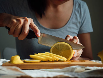 Midsection of woman cutting lemon on board