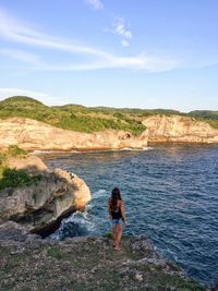 High angle view of woman standing on cliff against sea