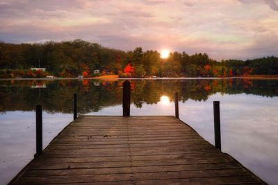 Pier over lake against sky during sunset