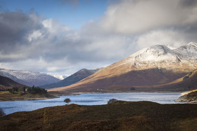 Scenic view of lake by snowcapped mountains against sky