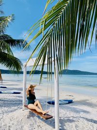 Full length of woman sitting on swing at beach