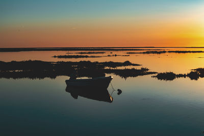 Boat on lake against sky during sunset