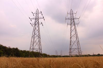 Electricity pylon on field against sky