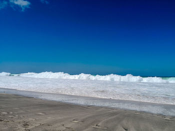 Scenic view of beach against blue sky