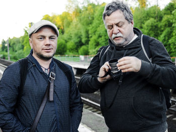 Male friends with camera standing on railroad track