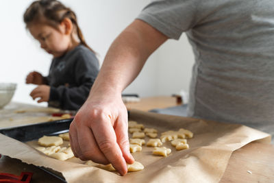 Cropped view of unrecognizable man and his daughter making sweets with biscuit cutters 