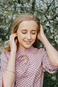 Blonde girl on a spring walk in the garden with cherry blossoms. female portrait, close-up.