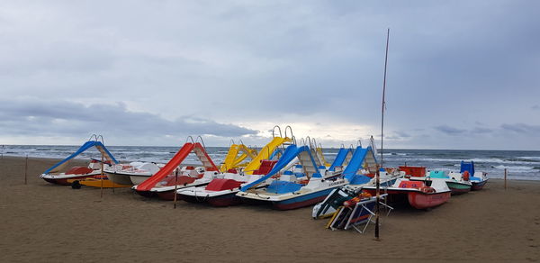 Sailboats moored on beach against sky