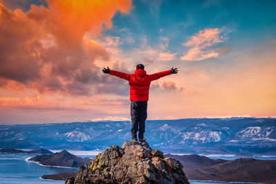 Man standing on rock against sky during sunset