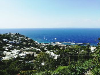 Aerial view of residential district by sea against sky