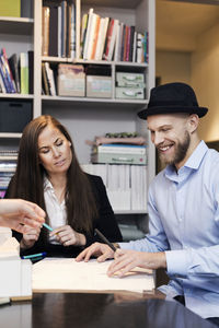 Male and female architects working on blueprint at desk in office