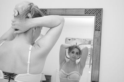 Portrait of sensuous woman with hand in hair reflecting on mirror at home