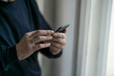 Close-up of senior man using cell phone at home