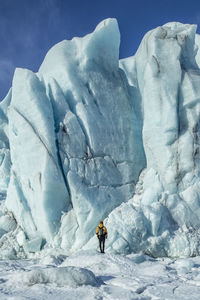 Back view of unrecognizable traveler hiker admiring spectacular scenery of frozen seashore with ice and snow in winter in iceland