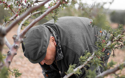 Old farmer is bended down working on an almond tree. close up. person