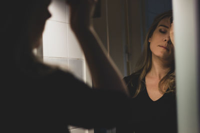 Beautiful woman applying make-up looking at mirror