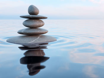 Stack of stones in sea against sky