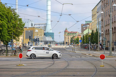 Cars on city street by buildings against sky