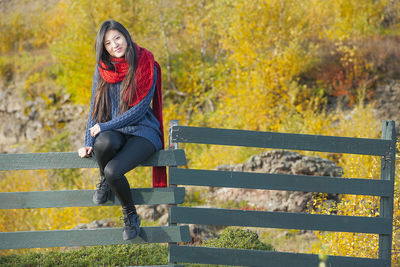 Beautiful woman sitting on a fence at the lake myvatn area