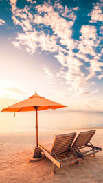 Lounge chairs at beach during sunset