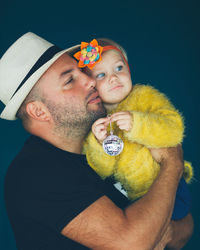 Portrait of father holding baby against black background