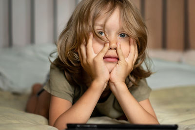 Boy lying on the bed using digital tablet computer playing games or watching cartoons at home.