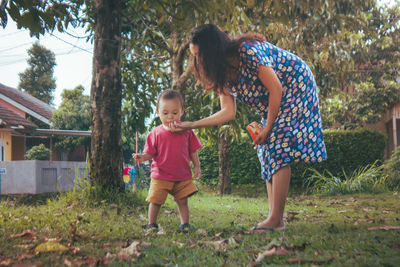 Full length of mother and daughter against trees