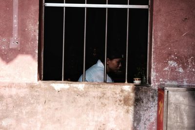 Side view of man looking through window in building