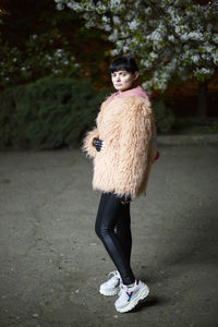 Full length portrait of woman standing against wall