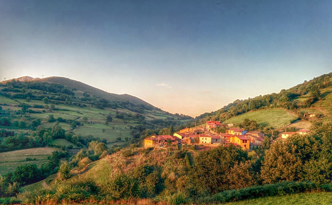 mountain, clear sky, landscape, tree, mountain range, scenics, tranquil scene, copy space, beauty in nature, tranquility, nature, high angle view, house, blue, building exterior, built structure, hill, architecture, idyllic, non-urban scene