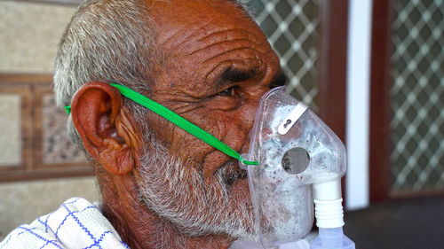 A elder person infected with covid 19 disease. patient inhaling oxygen wearing mask with liquid oxy