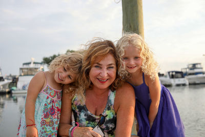 Portrait of smiling grandchildren with grandmother sitting at water