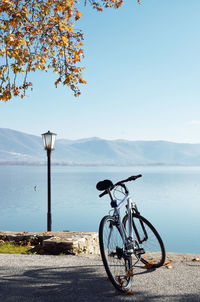 Bicycle by lake against sky