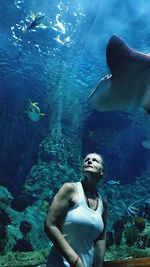 Woman looking at fishes swimming in sea