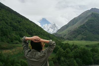 Rear view of man looking at mountains against sky