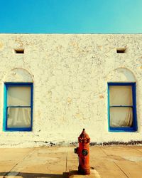 Old building against blue sky with red fire hydrant in front