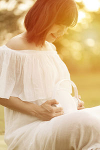 Midsection of woman holding white dress sitting outdoors