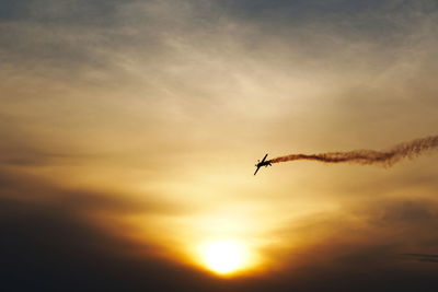 Low angle view of silhouette airplane flying against sky during sunset