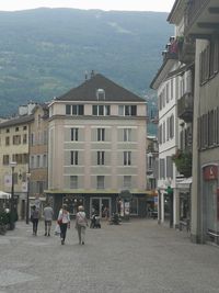 People walking on street amidst buildings in city